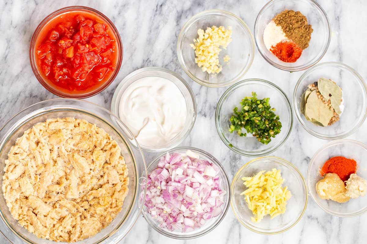 soy curls, ginger, tomatoes, and other curry ingredients in bowls on the kitchen counter