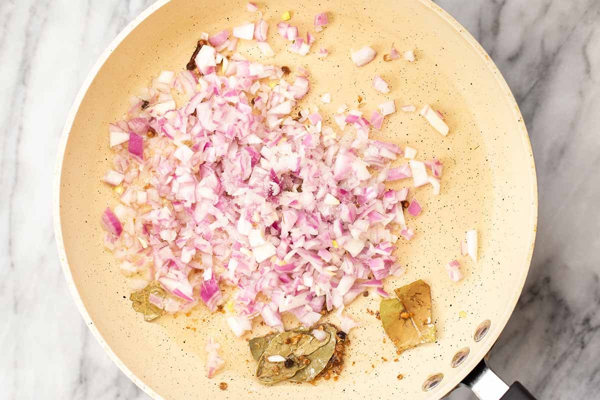 adding onion to the toasted whole spices in the pan