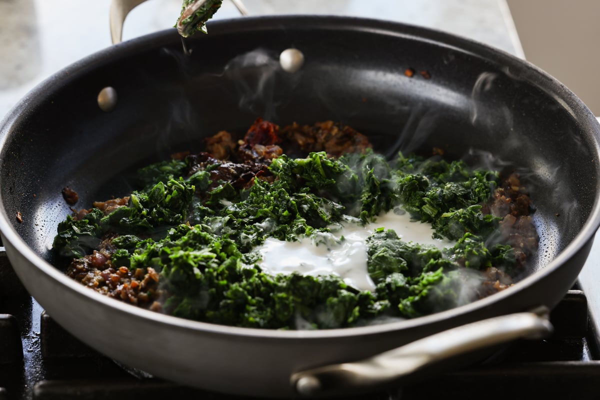 adding spinach and non-dairy yogurt to the pan