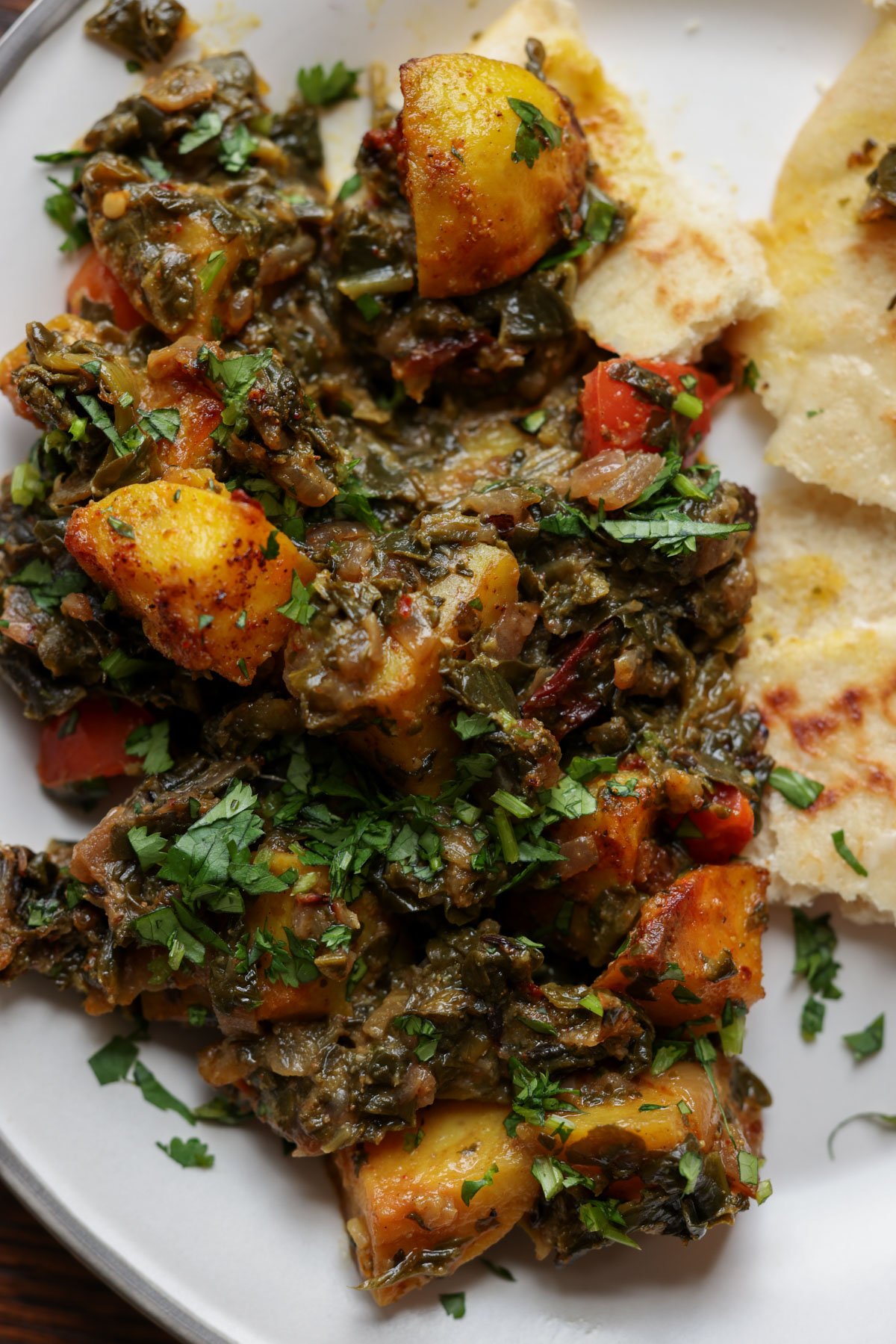 saag aloo on the plate with flatbread on the side