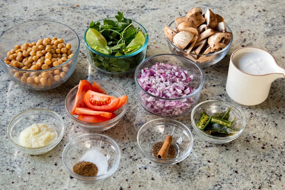 veggies, chickpeas, and spices in bowls on the kitchen counter