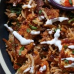 close-up of Lucknowi biryani in a bowl topped with raita