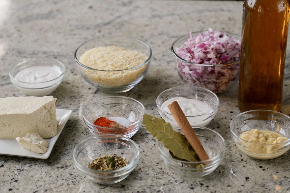 rice, spices, and other biryani ingredients in bowls on the kitchen counter