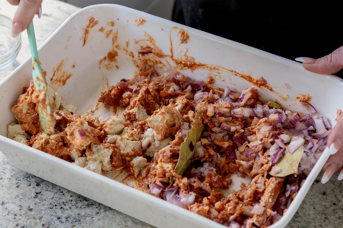 mixing tofu, onions, and spices . Tofu and onions are on separate sides of the pan