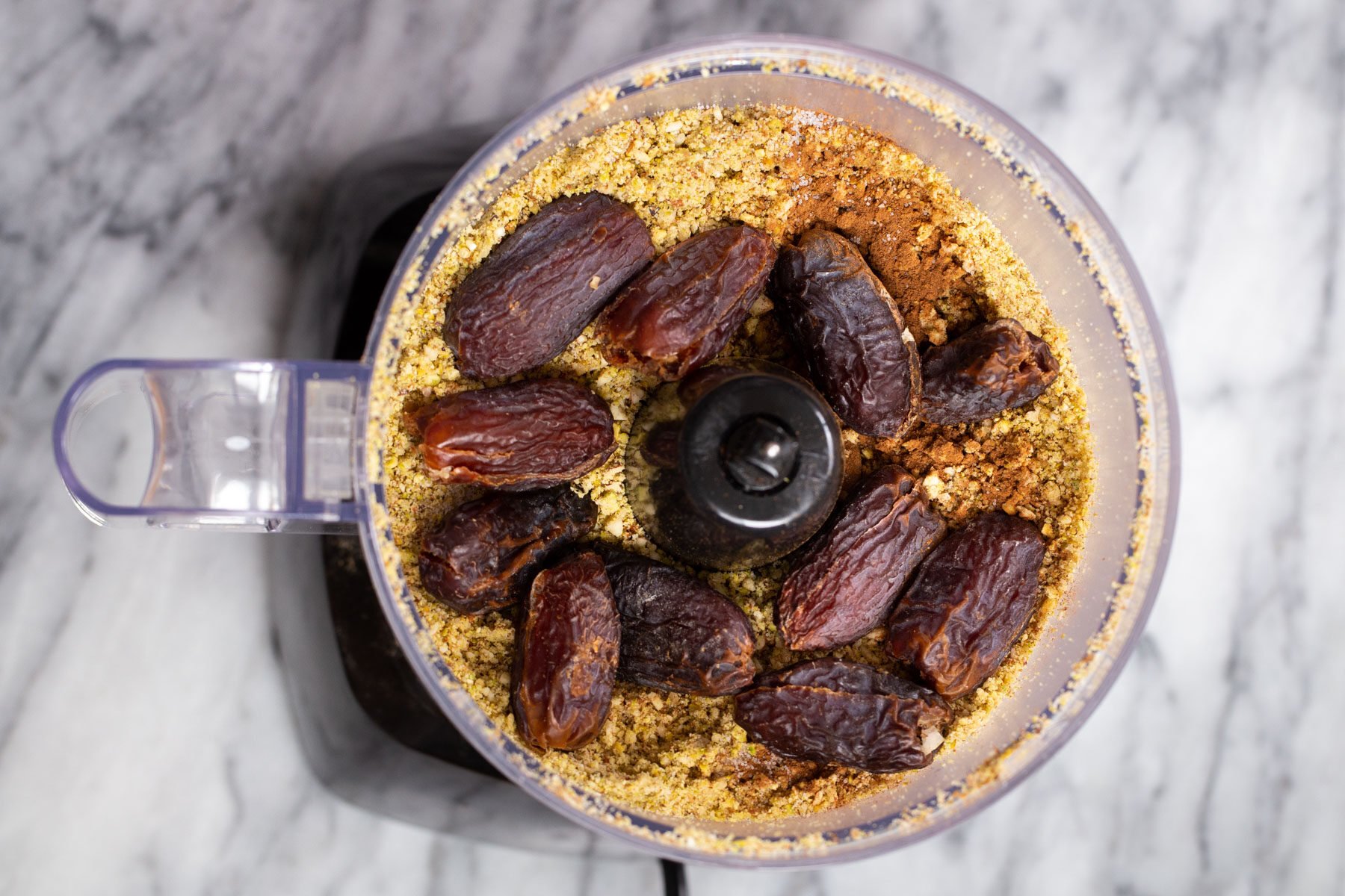 dates being added to ground nuts in a food processor 