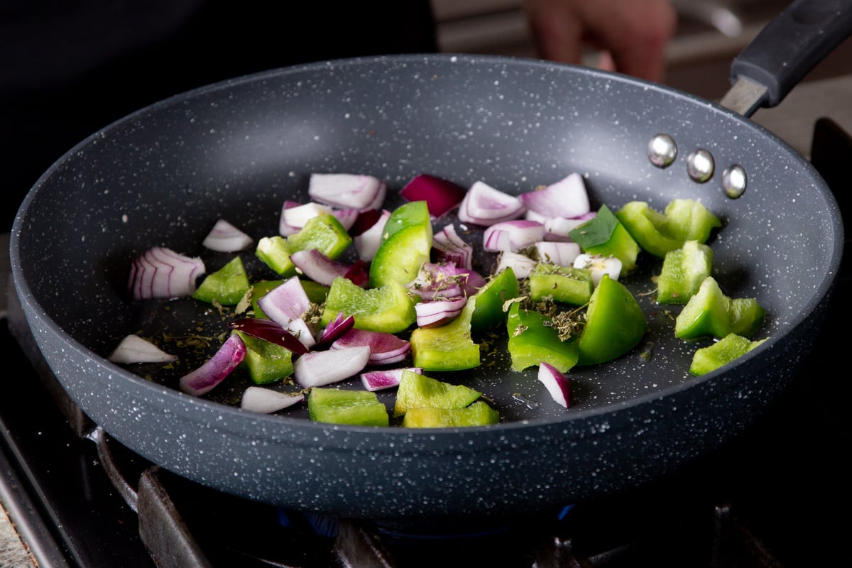 cooking the peppers and onions in the pan