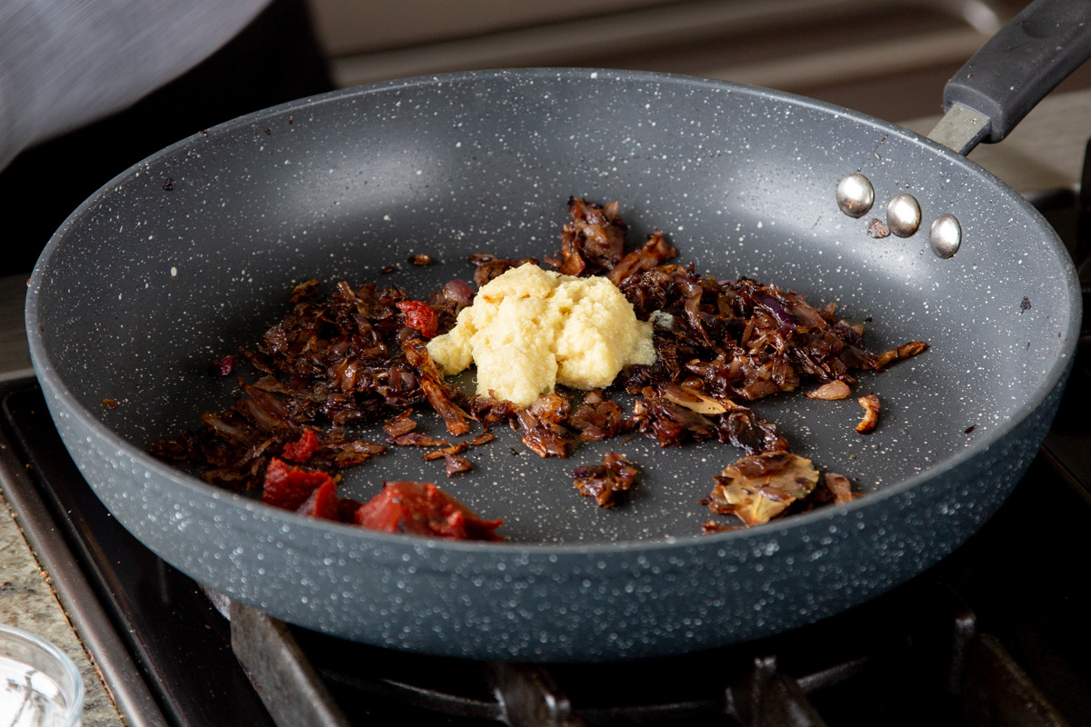 adding pastes to the pan of cooked onions