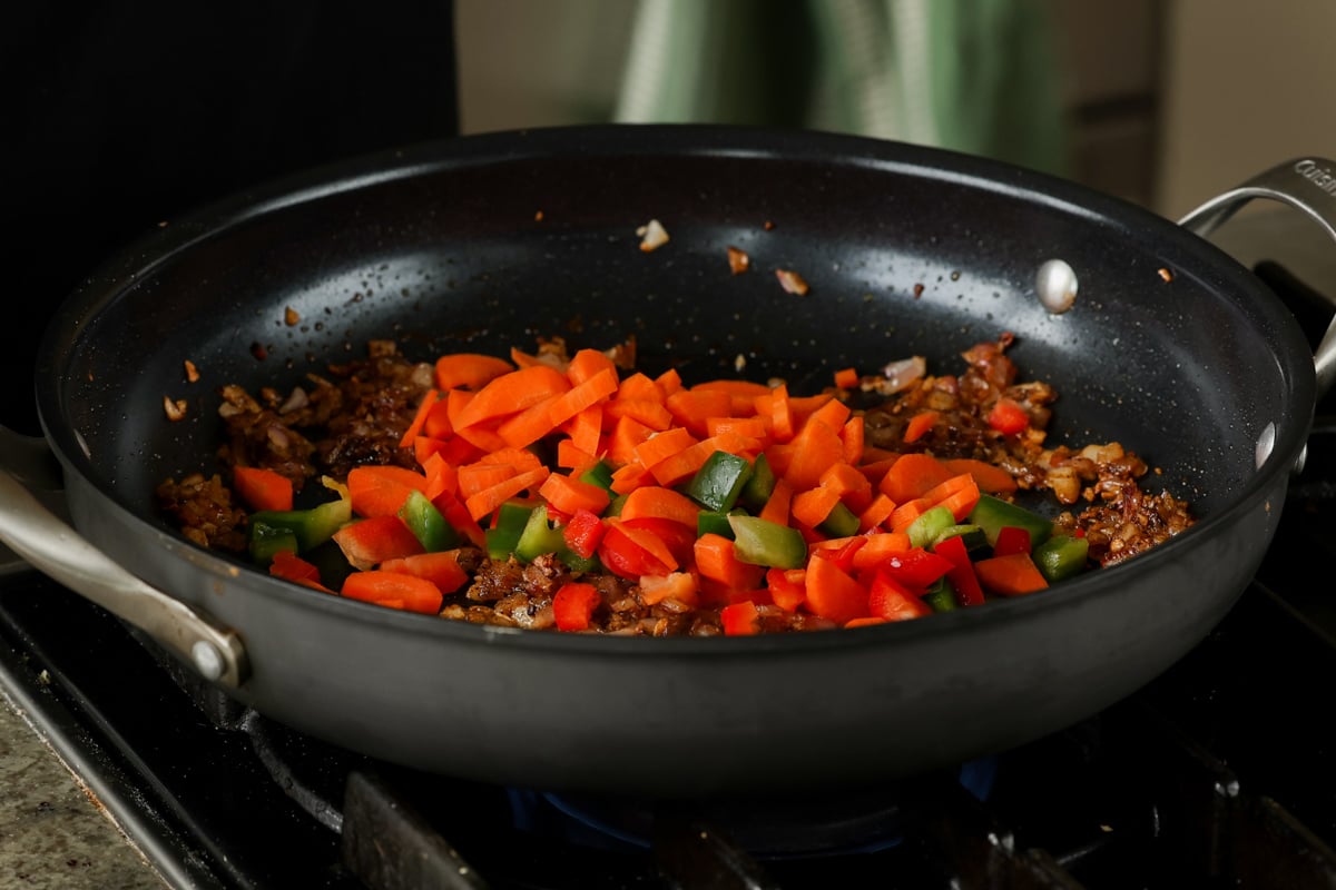 adding carrots and bell peppers to the pan