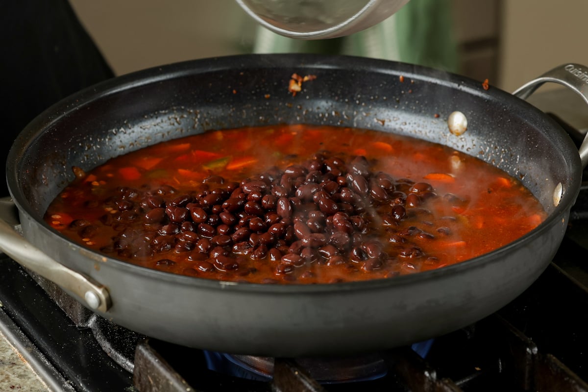adding black beans to the pan