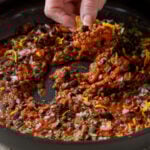 dipping a tortilla chip into the pan of black beans and lentils