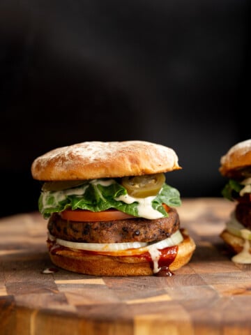 side view of a vegan black bean quinoa burger topped with vegan ranch and jalapenos