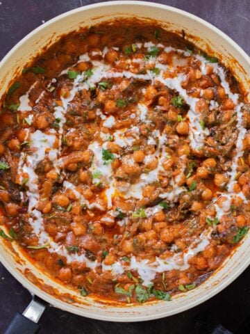 panful of harissa chickpeas after cooking with cilantro garnish and coconut cream swirl