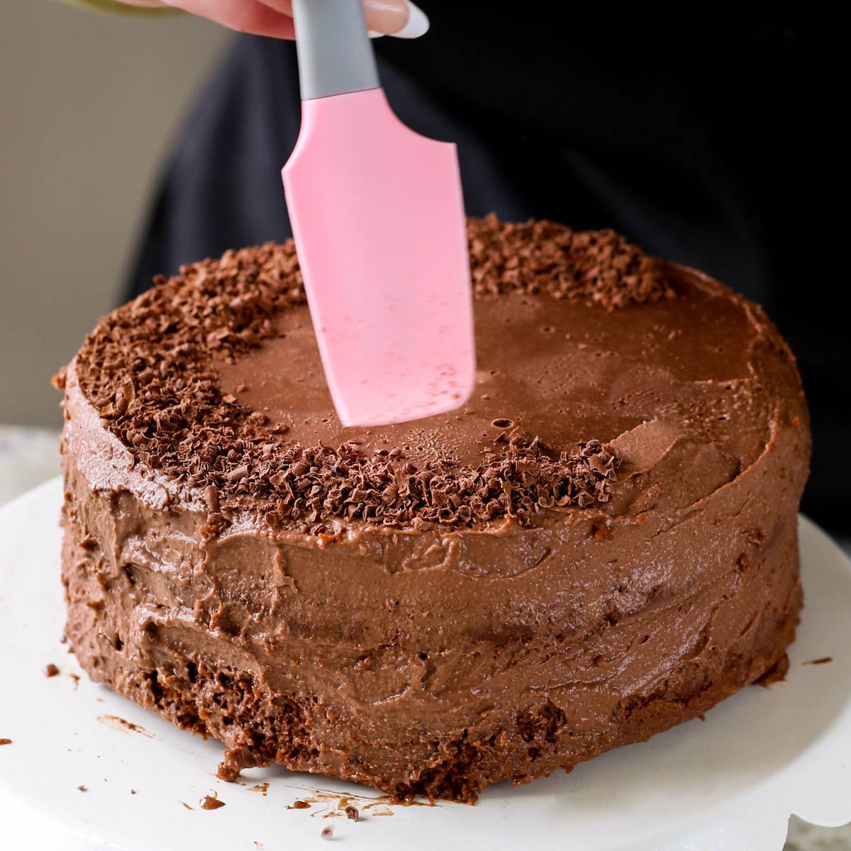 adding shaved chocolate to the mocha cake after frosting
