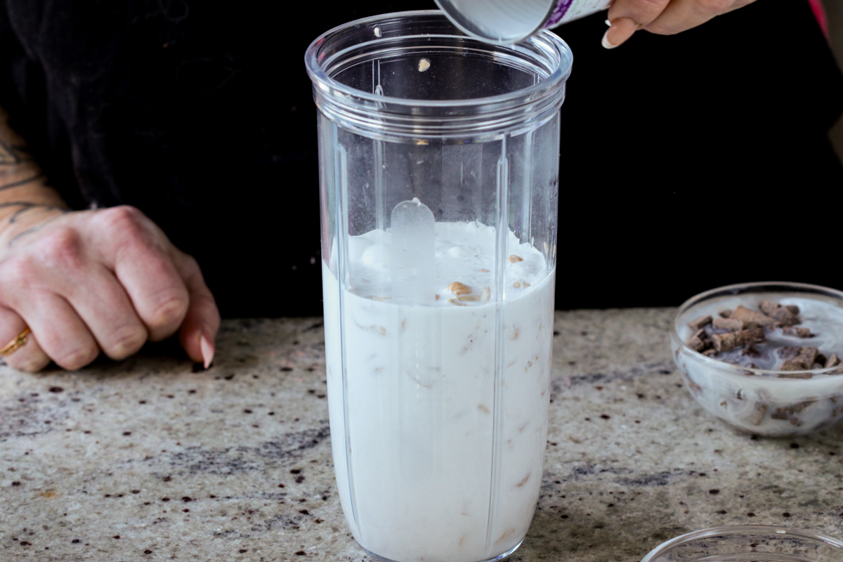 adding non-dairy milk to the cashews in the blender