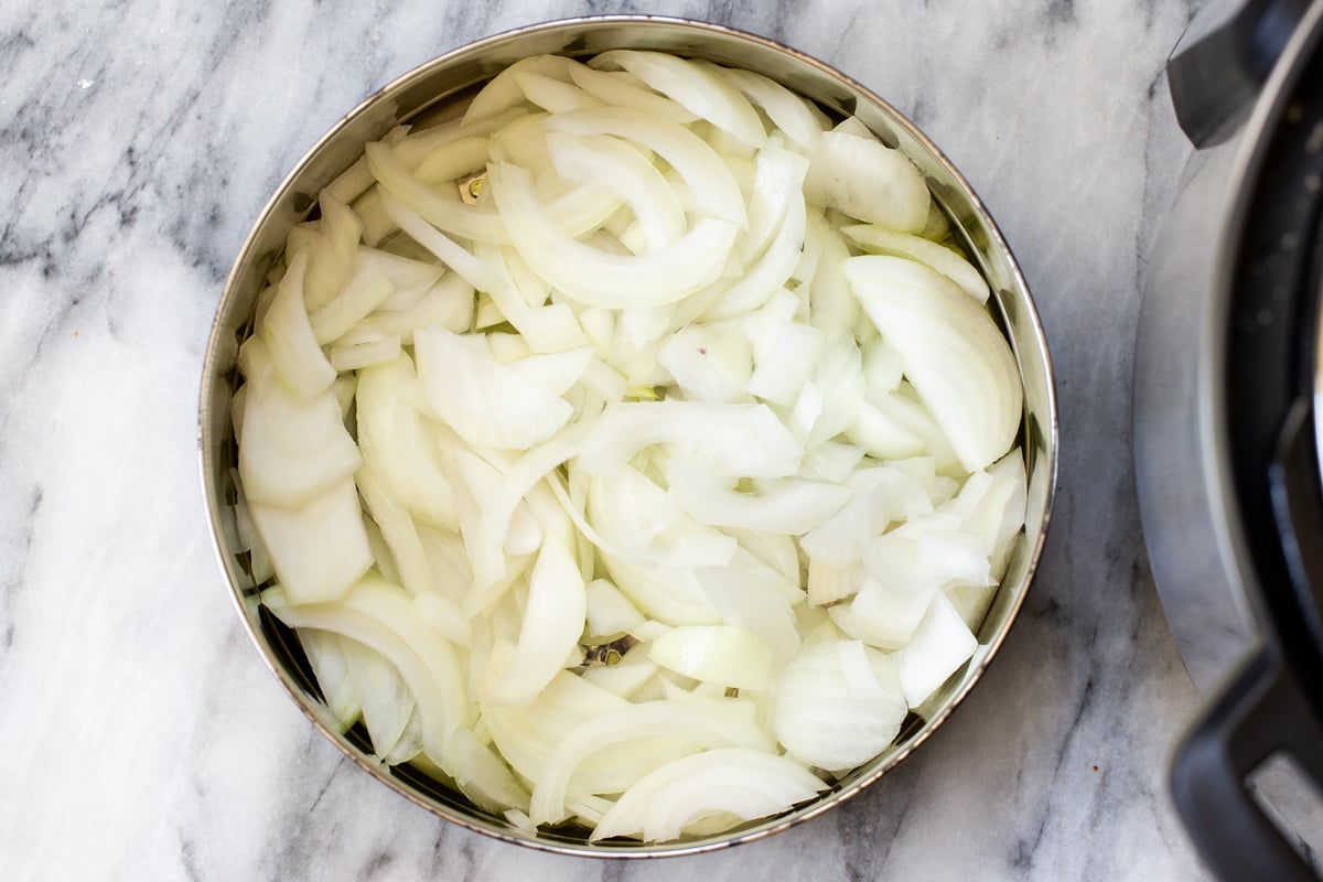 sliced yellow onion in the inner pot of an Instant Pot