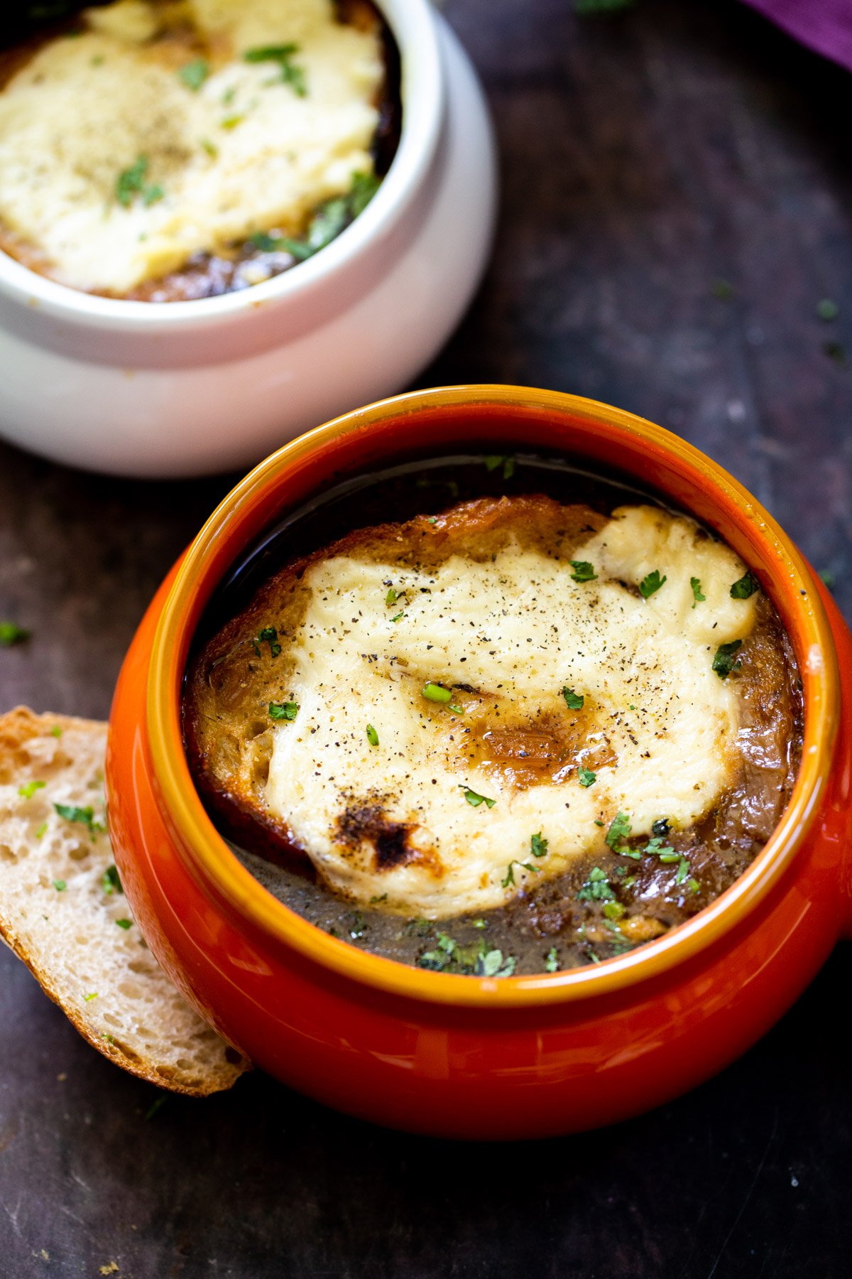 two small dishes with vegan French Onion Soup topped with vegan cheesy bread