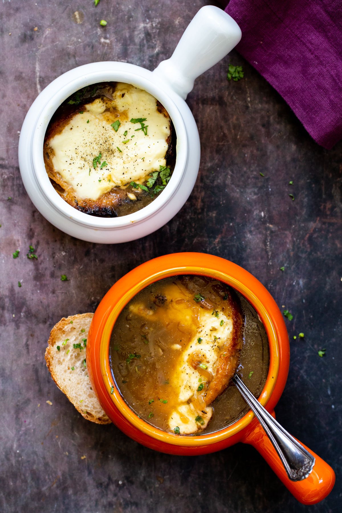 two servings of vegan French Onion Soup topped with cheesy bread 