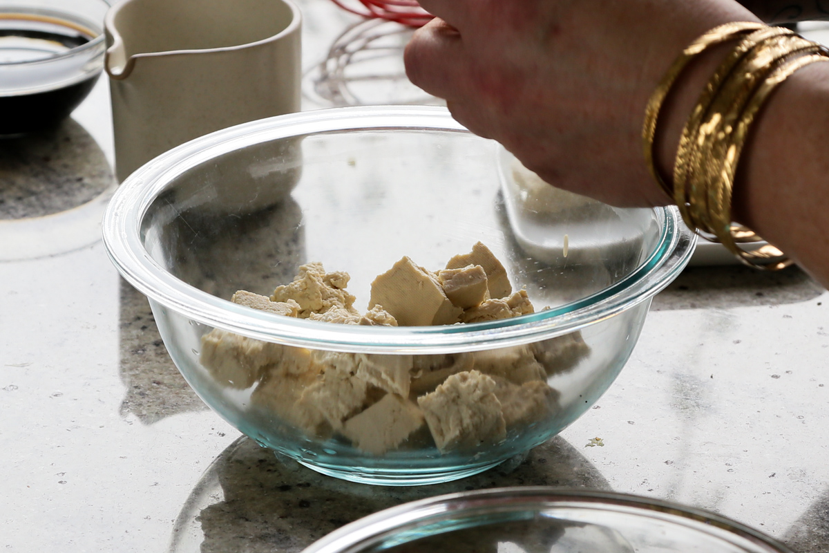 tearing tofu into pieces in a bowl