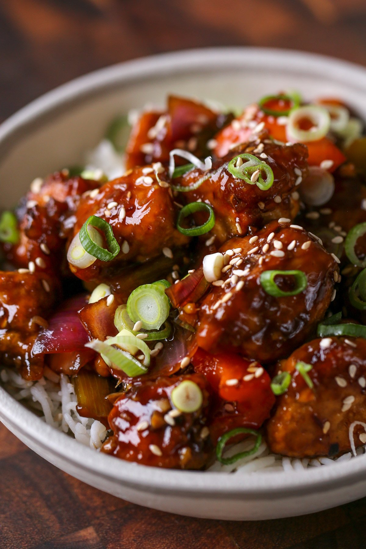 close-up of General Tso's tofu in a bowl with green onion and sesame seeds