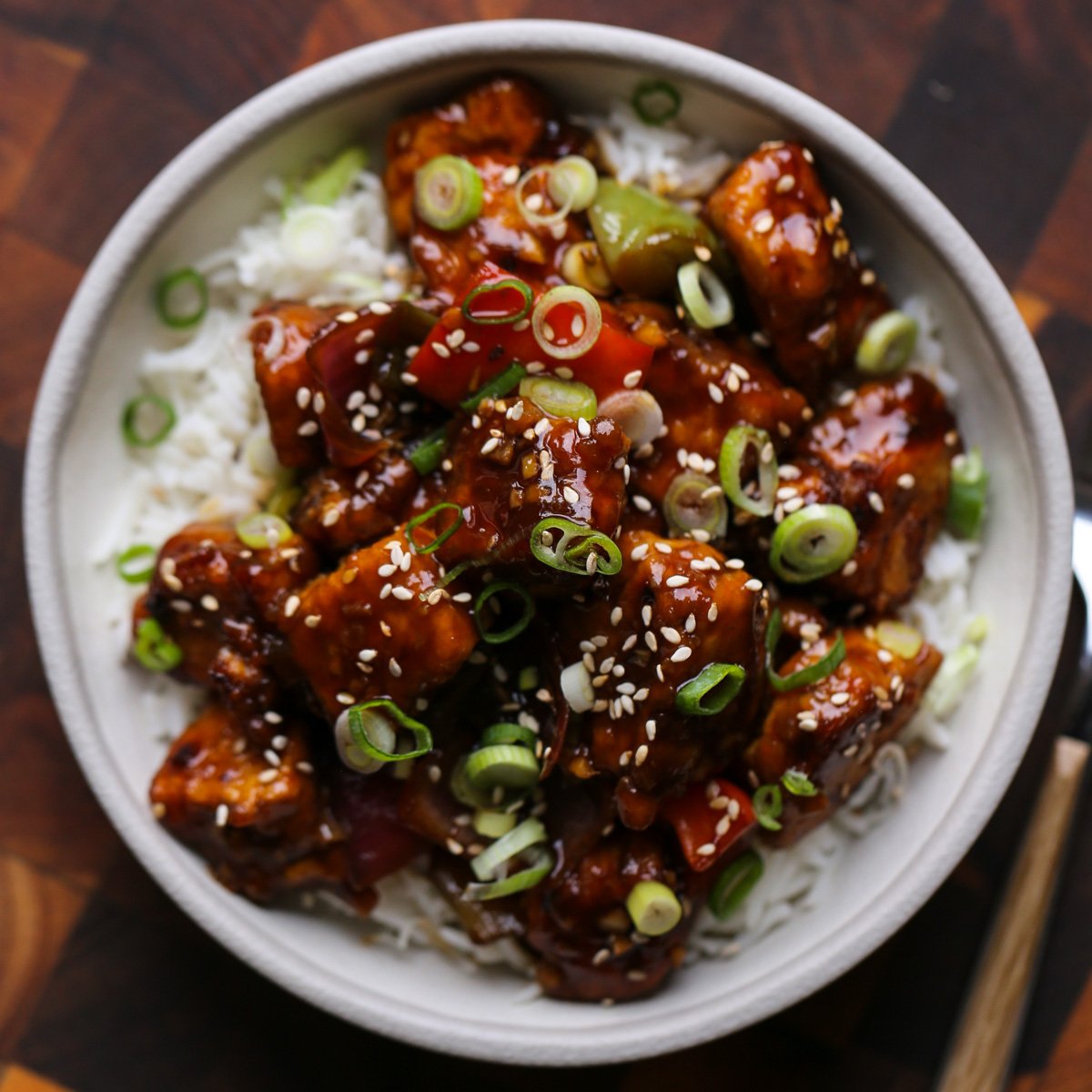 General Tso's tofu in a bowl with green onion and sesame seeds
