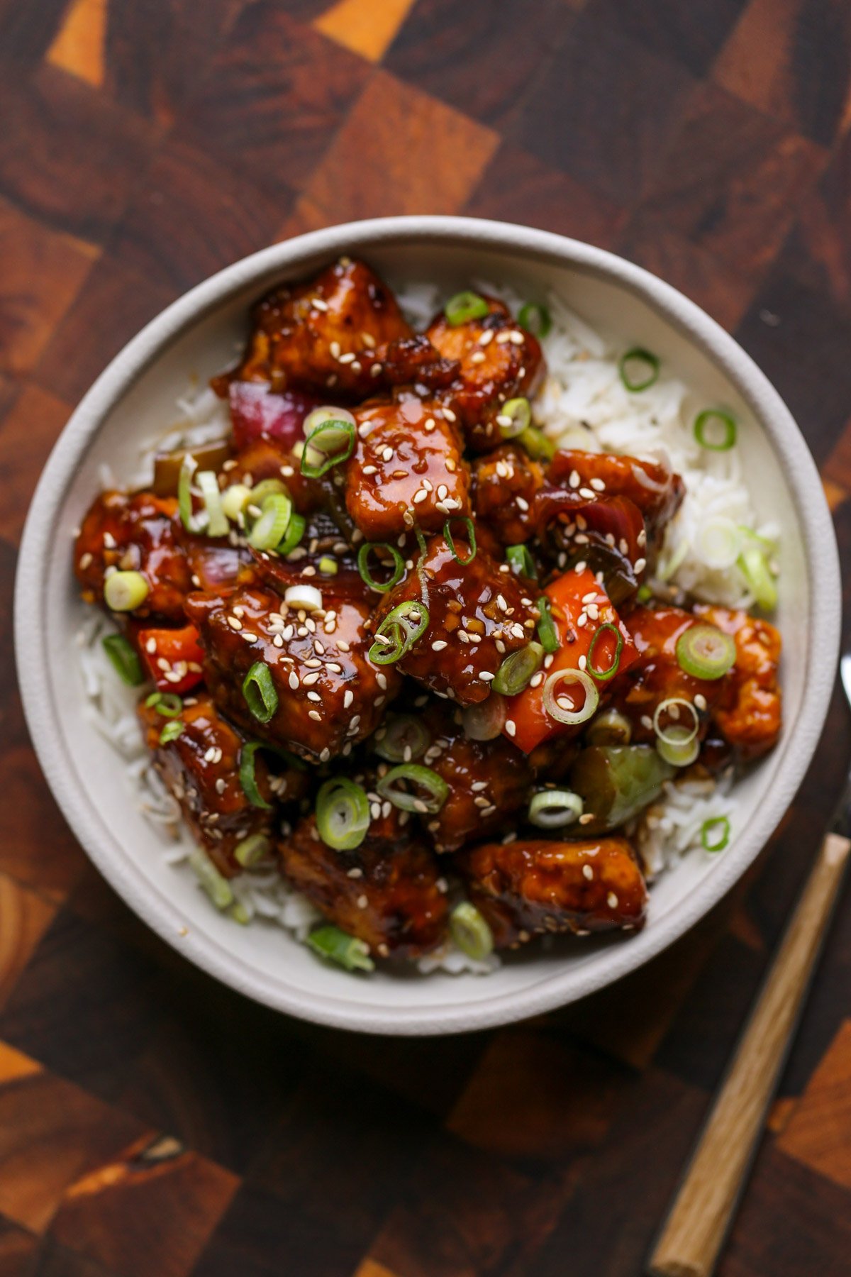 General Tso's tofu in a bowl with green onion and sesame seeds