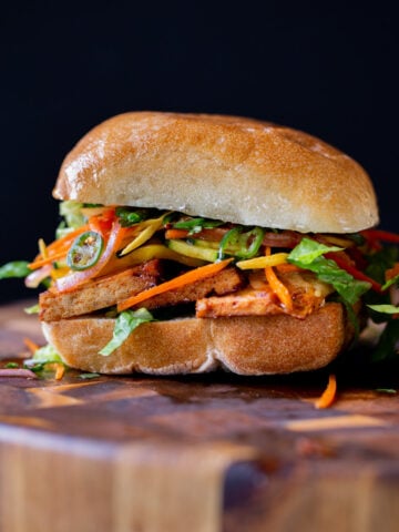gochujang sandwich with pickled veggies on a wooden cutting board