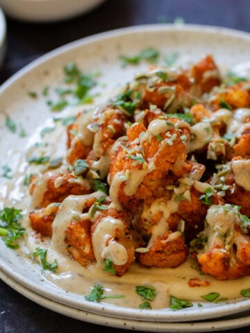 harissa cauliflower wrap tahini sauce on a bed of hummus