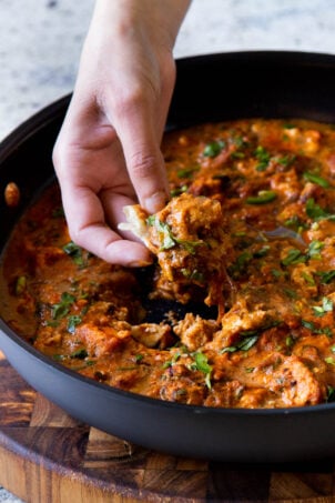 hand scooping up some Hyderabadi chicken curry on a piece of flatbread