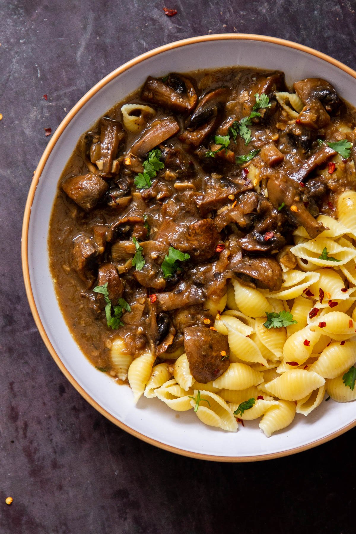 garlic mushrooms served alongside pasta in a white bowl 