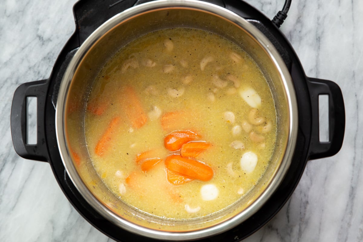 carrots and cashews being added to an Instant pot to make vegan cheese sauce