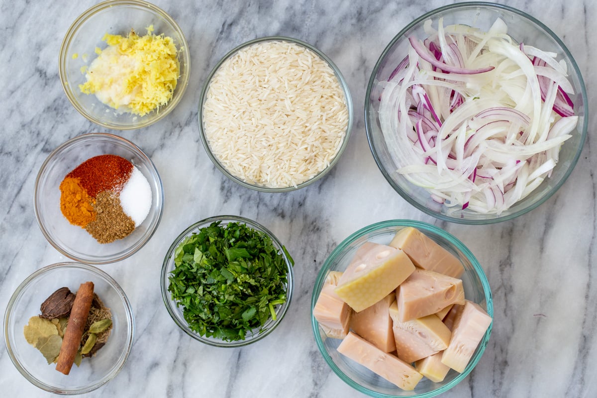 basmati rice, jackfruit, and other vegan biryani ingredients in bowls on the kitchen counter