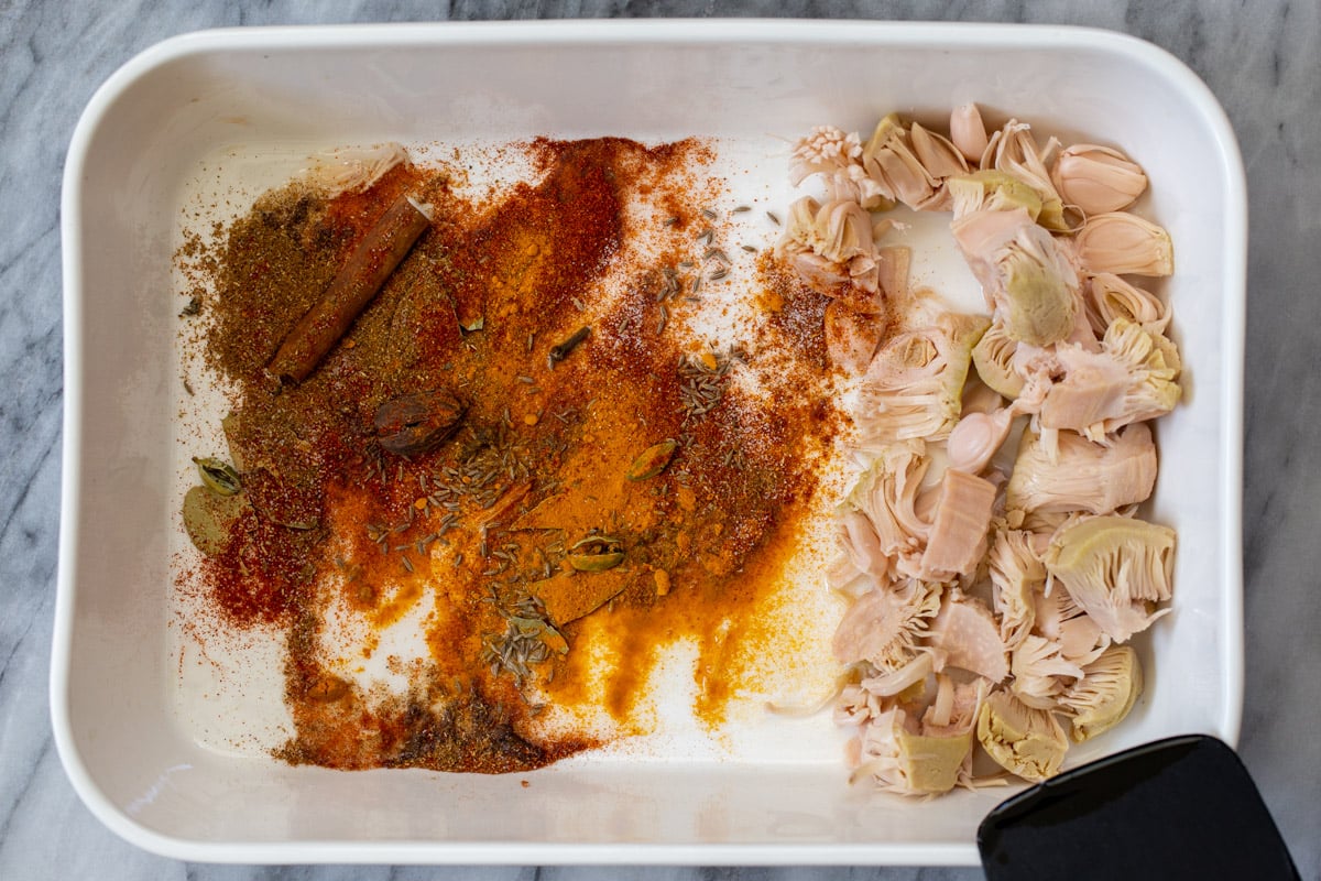 adding dried spices to the pan of jackfruit