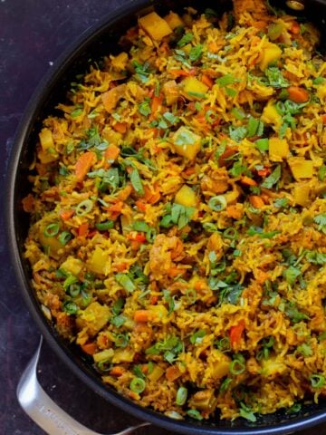 Jamaican curry rice in the pan with cilantro and green onions