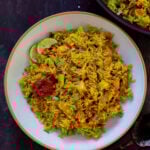 bowl of Jamaican curry rice with hot sauce and lime