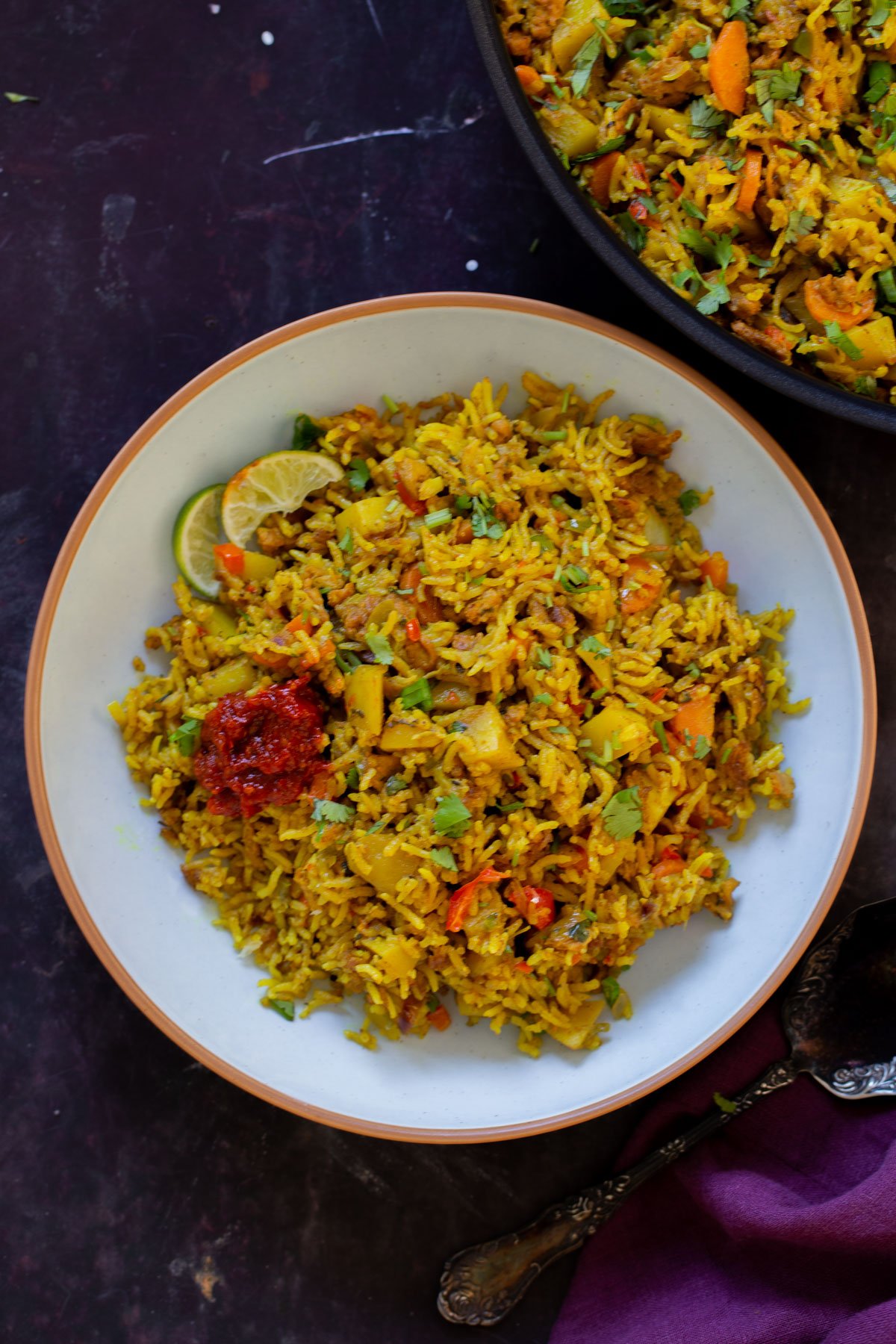 bowl of Jamaican curry rice with hot sauce and lime