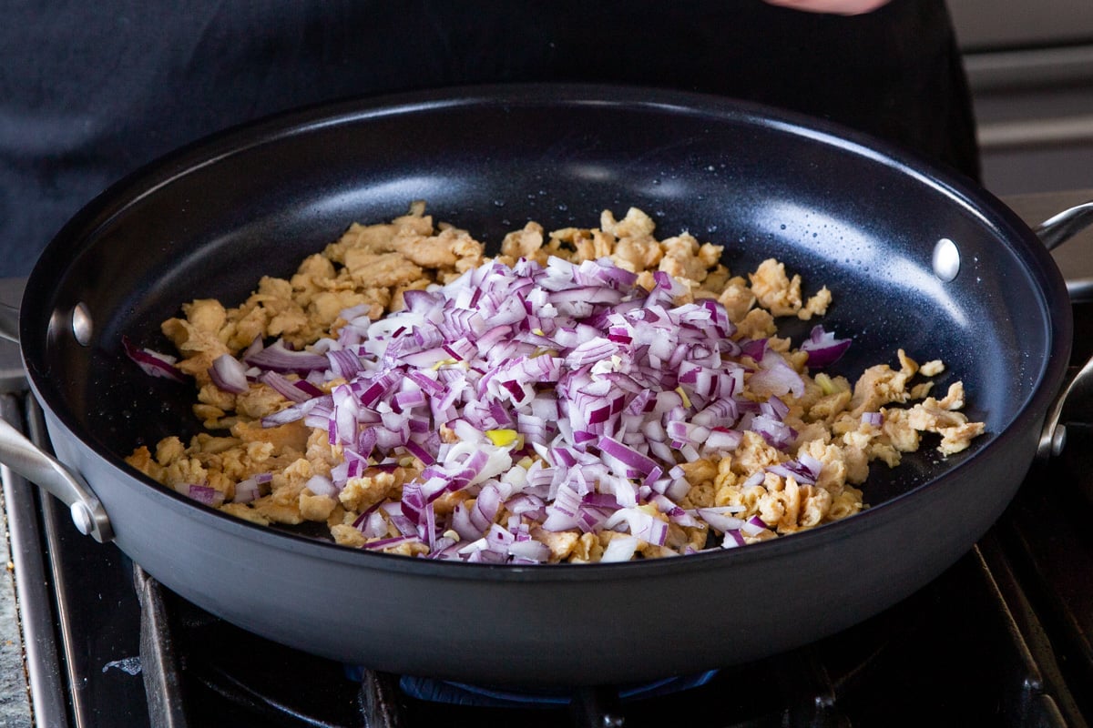soy curls and onions in the pan before cooking