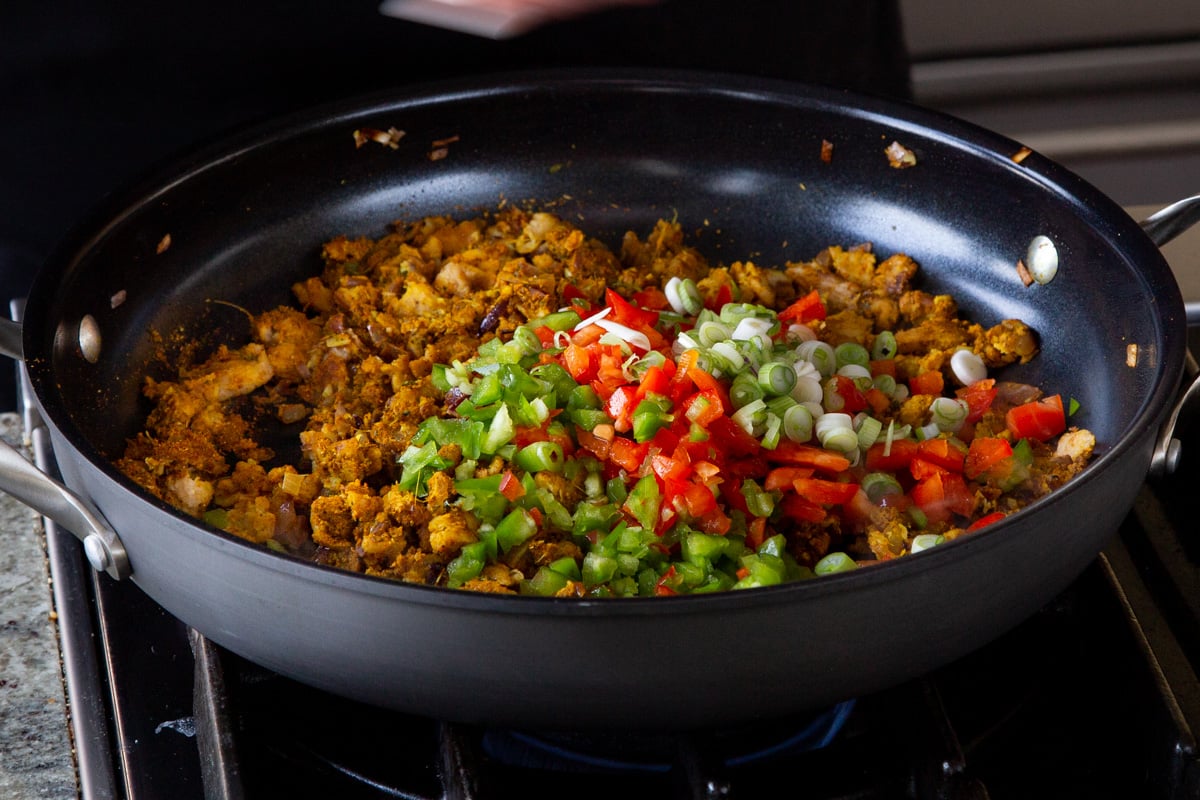adding bell pepper and green onion to the pan