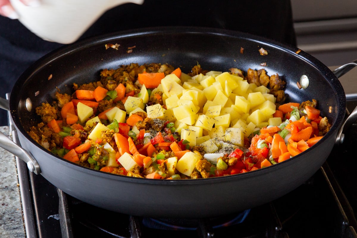 adding potatoes and a splash of water to the pan