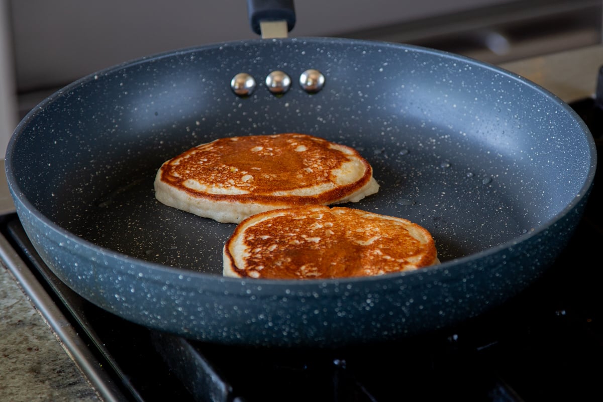 gluten-free lemon blueberry pancakes in the pan after flipping