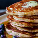 close-up of a stack of gluten-free lemon blueberry pancakes on a plate with blueberries