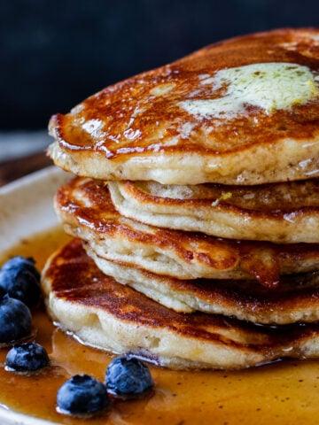 close-up of a stack of gluten-free lemon blueberry pancakes on a plate with blueberries