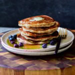 stack of gluten-free lemon blueberry pancakes on a plate with blueberries