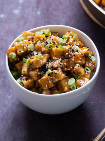 bowl of lemon pepper tofu topped with sesame seeds and green onions