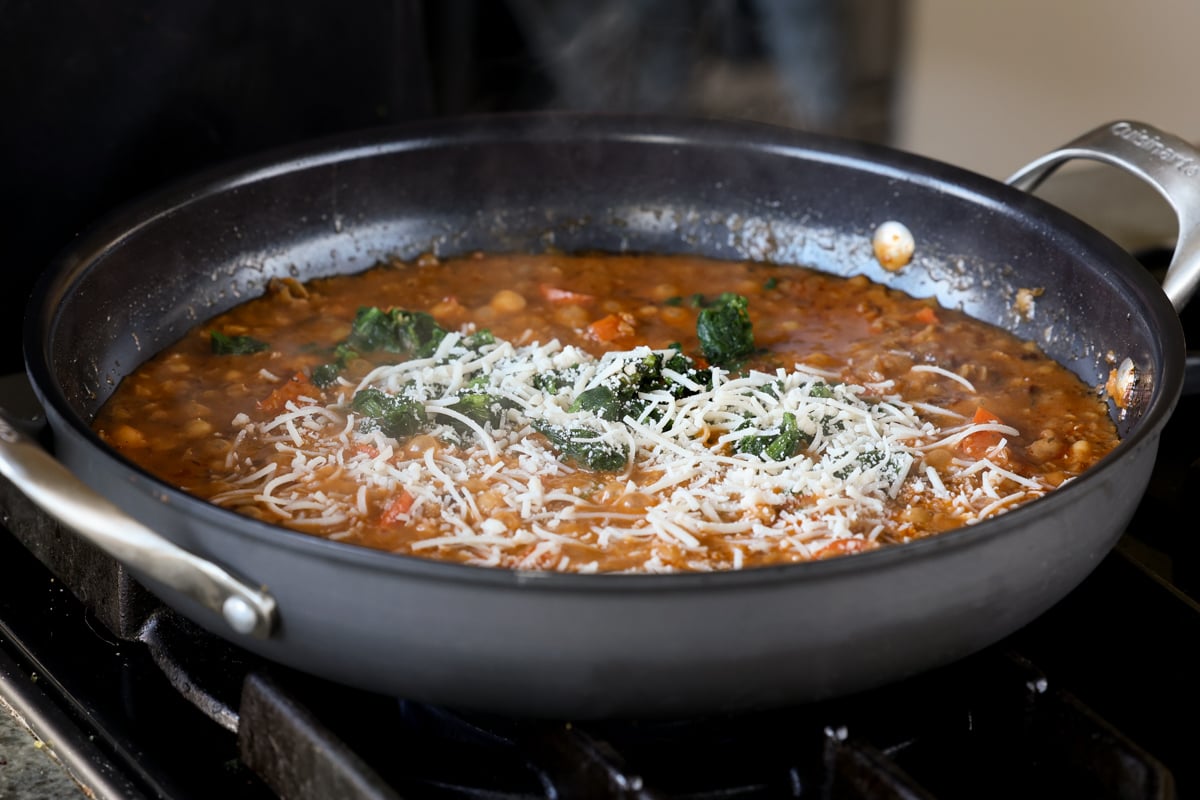adding spinach and vegan parmesan to the pan