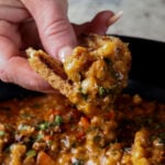 close-up of dipping a piece of toast into lentil chickpea stew