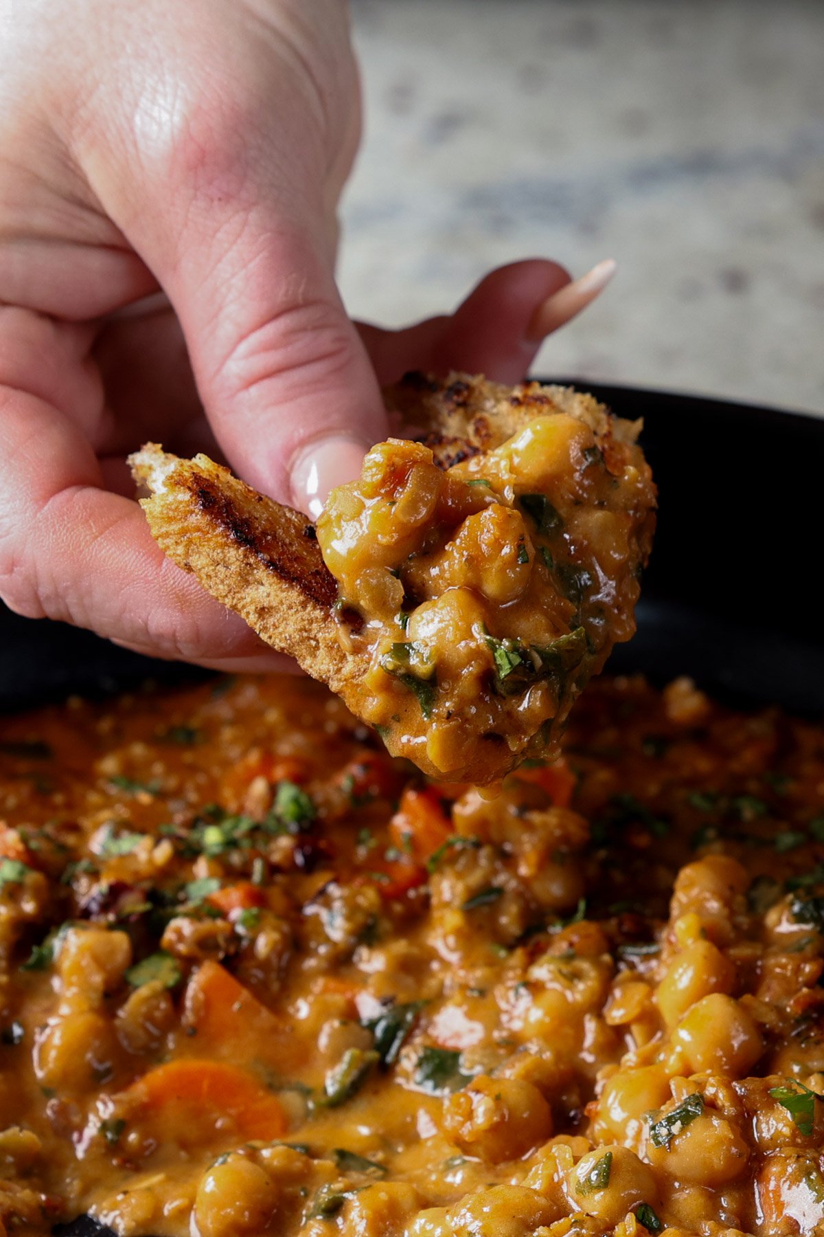 close-up of dipping a piece of toast into lentil chickpea stew