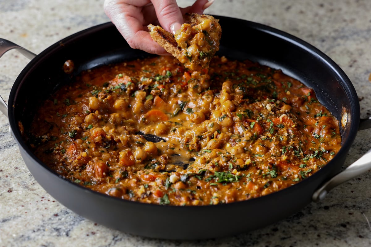 dipping a piece of toast into lentil chickpea stew