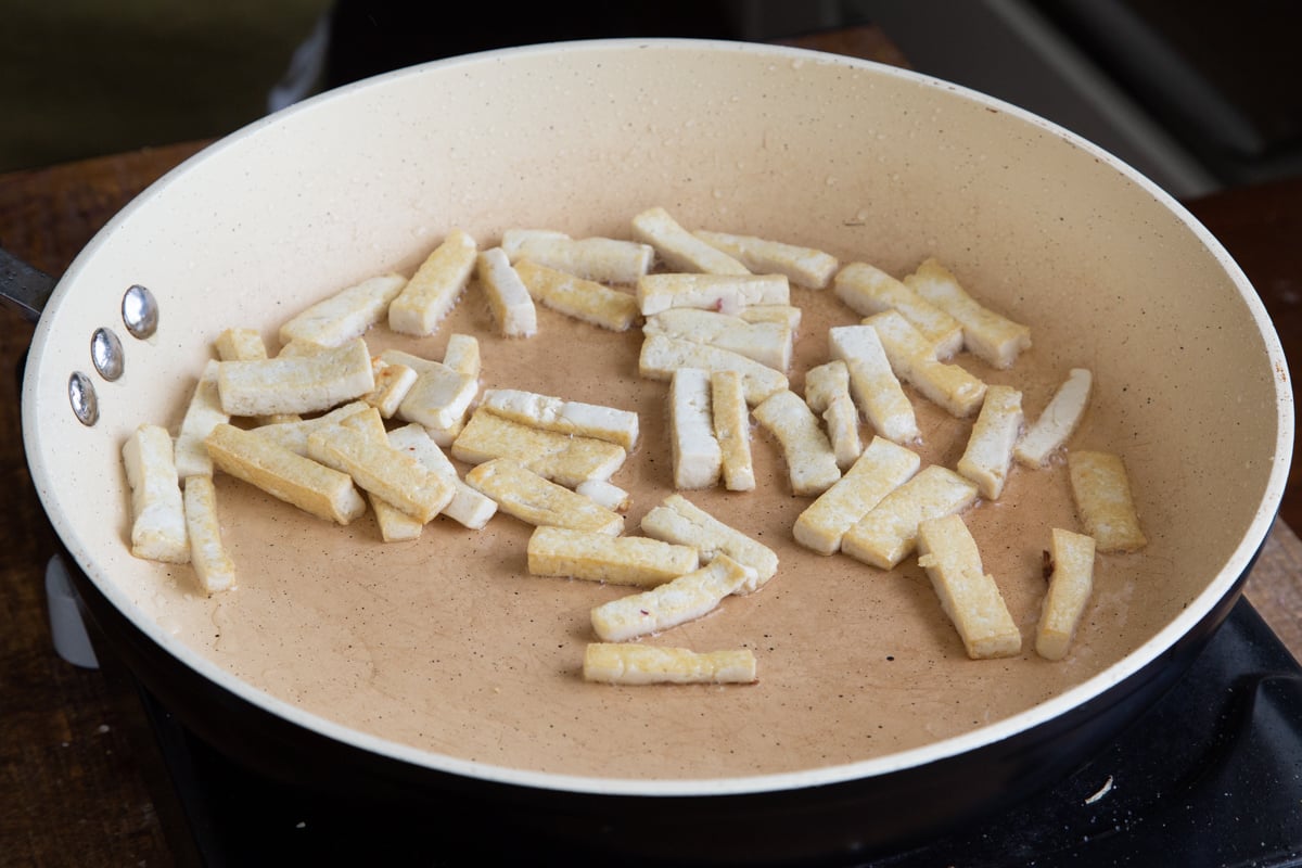 tofu pieces being fried in a pan 