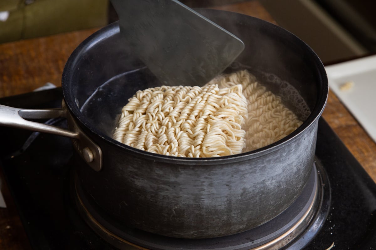 ramen noodles being cooked in a metal pot