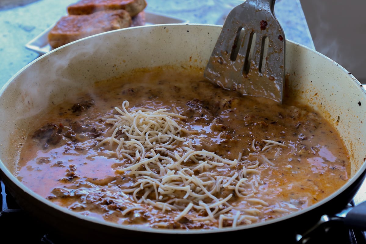 adding vegan parmesan to the pan